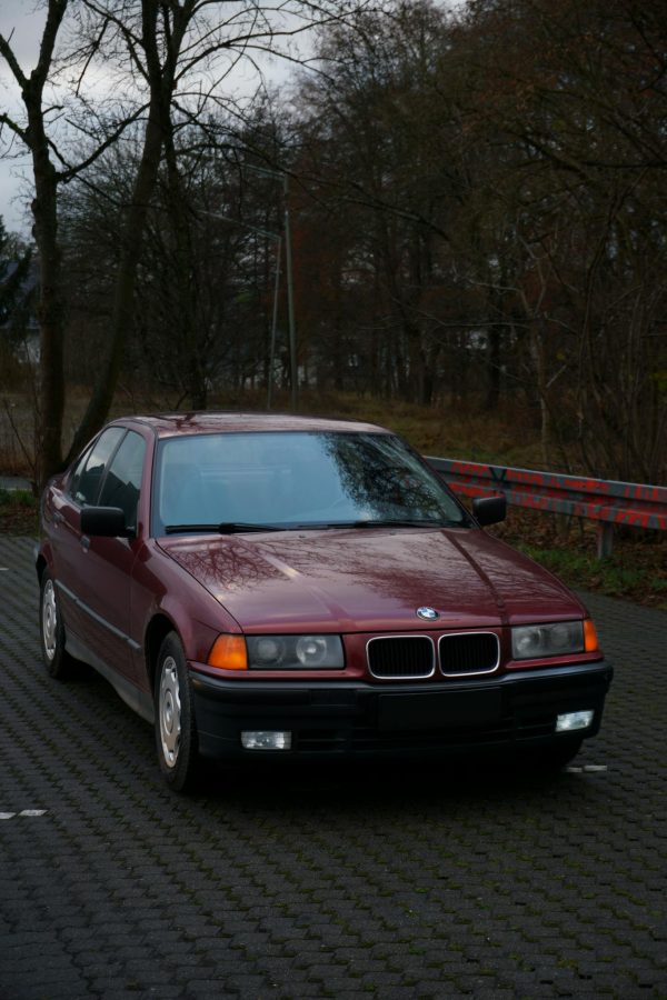 A classic red BMW parked in a scenic outdoor setting in Waldbröl, Germany.