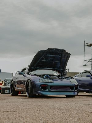 Toyota Supra with hood up on display at an outdoor car event.